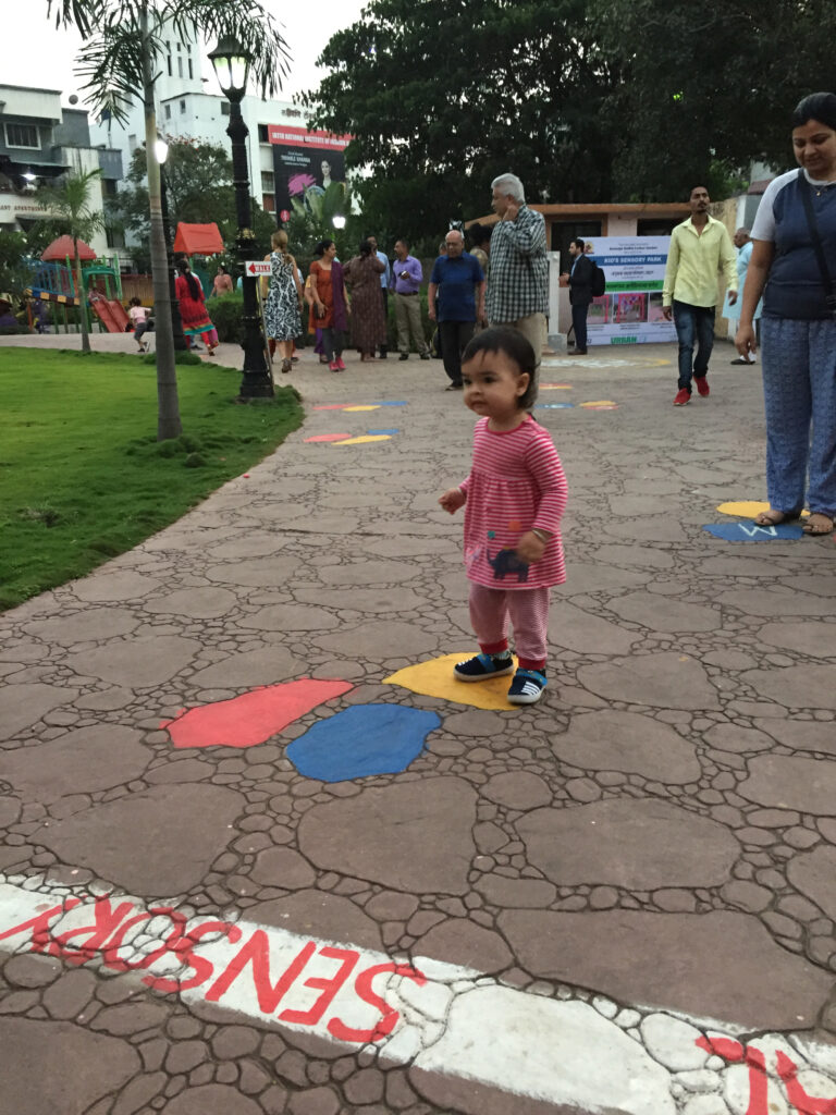 Young child playing on colourful pathway with a caregiver